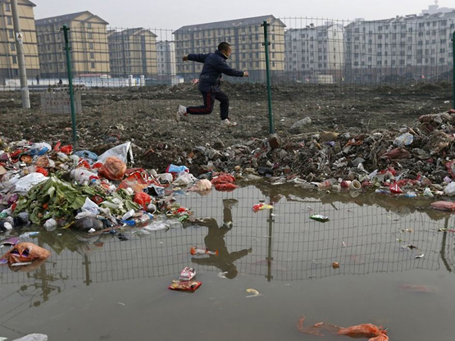 A child is reflected in a drainage ditch as he jumps over trash at a village which will soon be demolished, on the outskirts of Jiaxing city, Zhejiang province, January 12, 2013 A child is reflected in a drainage ditch as he jumps over trash at a village which will soon be demolished, on the outskirts of Jiaxing city, Zhejiang province, January 12, 2013