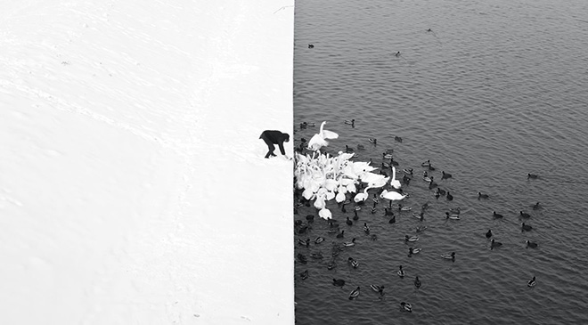 Marcin Ryczek - Krakow, from the Grunwald Bridge, Open Monochrome category. The nature-created contrast of white snow and dark water, the two separated by a straight line of the waterfront, serves as a reflection of the Yin Yang symbol of opposing, yet complementary forces.