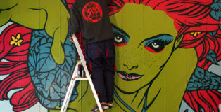 Solo e Diamond, Listen to me Ivy 2021, murale, Via Dina Galli 8, Roma dettaglio con Solo mentre dipinge Poison Ivy, progetto Another World. photo credit: LAP