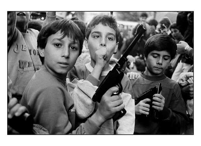 Letizia Battaglia - Palermo, 1986. Festa del giorno dei morti. I bambini giocano con le armi