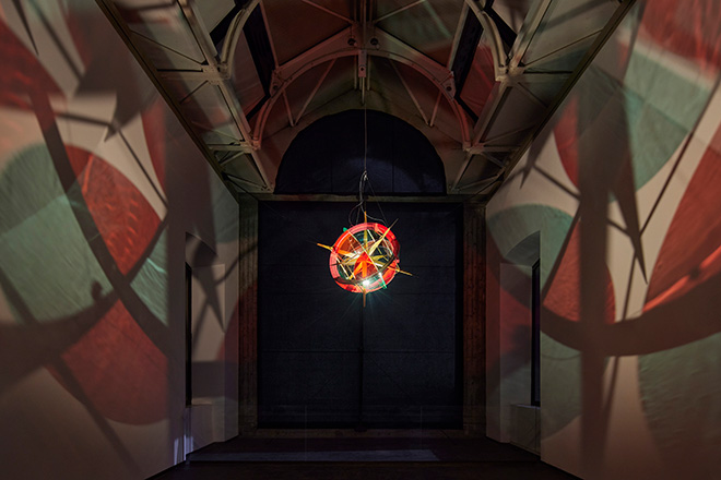 Navigation star for utopia, 2022 - Stainless steel, wood (oak), colored glass (red, green), brass, paint (gray, black, red), LED lights (white) ø 137 cm. Installation view: Olafur Eliasson: Orizzonti tremanti, Castello di Rivoli – Museo d'Arte Contemporanea, Italy, 2022 Photo: Agostino Osio. Courtesy of the artist; neugerriemschneider, Berlin; Tanya Bonakdar Gallery, New York / Los Angeles