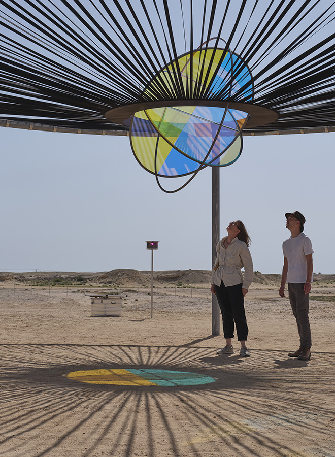 Slow solar event, 2023. Galvanized steel, stainless steel, paint (black, grey), polypropylene strapping, laminated colour-effect filter glass (cyan, magenta, yellow). 380 x 950 x 950 cm. Installation view: Olafur Eliasson: The curious desert, near the Al Thakhira Mangrove in Northern Qatar, 2023. Photo: Ander Sune Berg. Courtesy of the artist; neugerriemschneider, Berlin; Tanya Bonakdar Gallery, New York / Los Angeles.