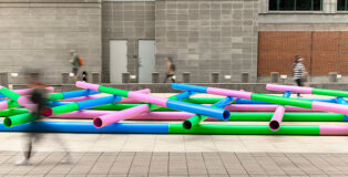 Julia Jamrozik and Coryn Kempster, Pipelines, 2023. Site-specific installation composed of PVC water and wastewater infrastructure pipes. Plaza of the Americas, Denver, Colorado. Presented by the Biennial of the Americas with artistic direction by Black Cube Nomadic Art Museum. Courtesy the artists and Black Cube. Photo: Third Dune Productions.