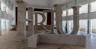 Shilpa Gupta, Truth, 2025 Legno, resina, cemento, Dimensioni totali: 14,50 x 8 m | 570.86 x 314.96 in, T: 327 x 405 x 75 cm | 128.74 x 159.44 x 29.52 in; H: 405 x 401 x 75 cm | 159.44 x 157.87 x 29.52 in; R: 265 x 401 x 75 cm | 104.33 x 157.87 x 29.52 in; U: 398 x 409 x 75 cm | 159.69 x 161.02 x 29.52 in; T: 327 x 405 x 75 cm | 129.74 x 159.44 x 29.52 in, Courtesy: l’artista e GALLERIA CONTINUA. Fotografa: Ela Bialkowska, OKNO Studio