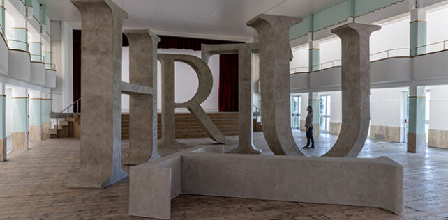 Shilpa Gupta, Truth, 2025 Legno, resina, cemento, Dimensioni totali: 14,50 x 8 m | 570.86 x 314.96 in, T: 327 x 405 x 75 cm | 128.74 x 159.44 x 29.52 in; H: 405 x 401 x 75 cm | 159.44 x 157.87 x 29.52 in; R: 265 x 401 x 75 cm | 104.33 x 157.87 x 29.52 in; U: 398 x 409 x 75 cm | 159.69 x 161.02 x 29.52 in; T: 327 x 405 x 75 cm | 129.74 x 159.44 x 29.52 in, Courtesy: l’artista e GALLERIA CONTINUA. Fotografa: Ela Bialkowska, OKNO Studio Shilpa Gupta, Galleria Continua / San Gimignano