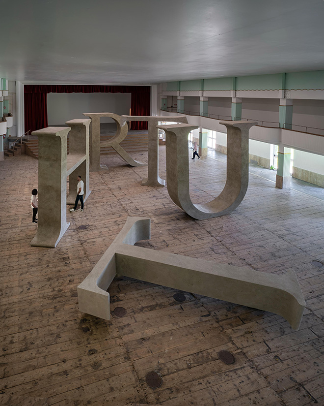 Shilpa Gupta, Truth, 2025 Legno, resina, cemento, Dimensioni totali: 14,50 x 8 m | 570.86 x 314.96 in, T: 327 x 405 x 75 cm | 128.74 x 159.44 x 29.52 in; H: 405 x 401 x 75 cm | 159.44 x 157.87 x 29.52 in; R: 265 x 401 x 75 cm | 104.33 x 157.87 x 29.52 in; U: 398 x 409 x 75 cm | 159.69 x 161.02 x 29.52 in; T: 327 x 405 x 75 cm | 129.74 x 159.44 x 29.52 in, Courtesy: l’artista e GALLERIA CONTINUA. Fotografa: Ela Bialkowska, OKNO Studio Shilpa Gupta, Truth, 2025 Legno, resina, cemento, Dimensioni totali: 14,50 x 8 m | 570.86 x 314.96 in, T: 327 x 405 x 75 cm | 128.74 x 159.44 x 29.52 in; H: 405 x 401 x 75 cm | 159.44 x 157.87 x 29.52 in; R: 265 x 401 x 75 cm | 104.33 x 157.87 x 29.52 in; U: 398 x 409 x 75 cm | 159.69 x 161.02 x 29.52 in; T: 327 x 405 x 75 cm | 129.74 x 159.44 x 29.52 in, Courtesy: l’artista e GALLERIA CONTINUA. Fotografa: Ela Bialkowska, OKNO Studio
