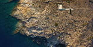 Aerial view of Horizon House nestled into the rocky coastline of Syros.. Photo credit: ONUS Architecture Studio