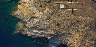 Aerial view of Horizon House nestled into the rocky coastline of Syros.. Photo credit: ONUS Architecture Studio ONUS Architecture Studio – Horizon House