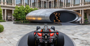 Audi at Milan Design Week 2026. Rear view of the Audi Formula 1 show car Audi R26 displayed on a circular platform. In the background, Audi’s installation “Origin” shown at Milan Design Week 2026. ©Audi AG