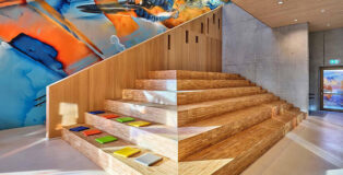 JSWD + Jim Clemes Ass. – Ecole Brouch: Primary School, Esch-sur-Alzette, Luxembourg. Entrance hall with seat steps, Artwork: Daniel Mac Lloyd. Photo credit: Andres Lejona